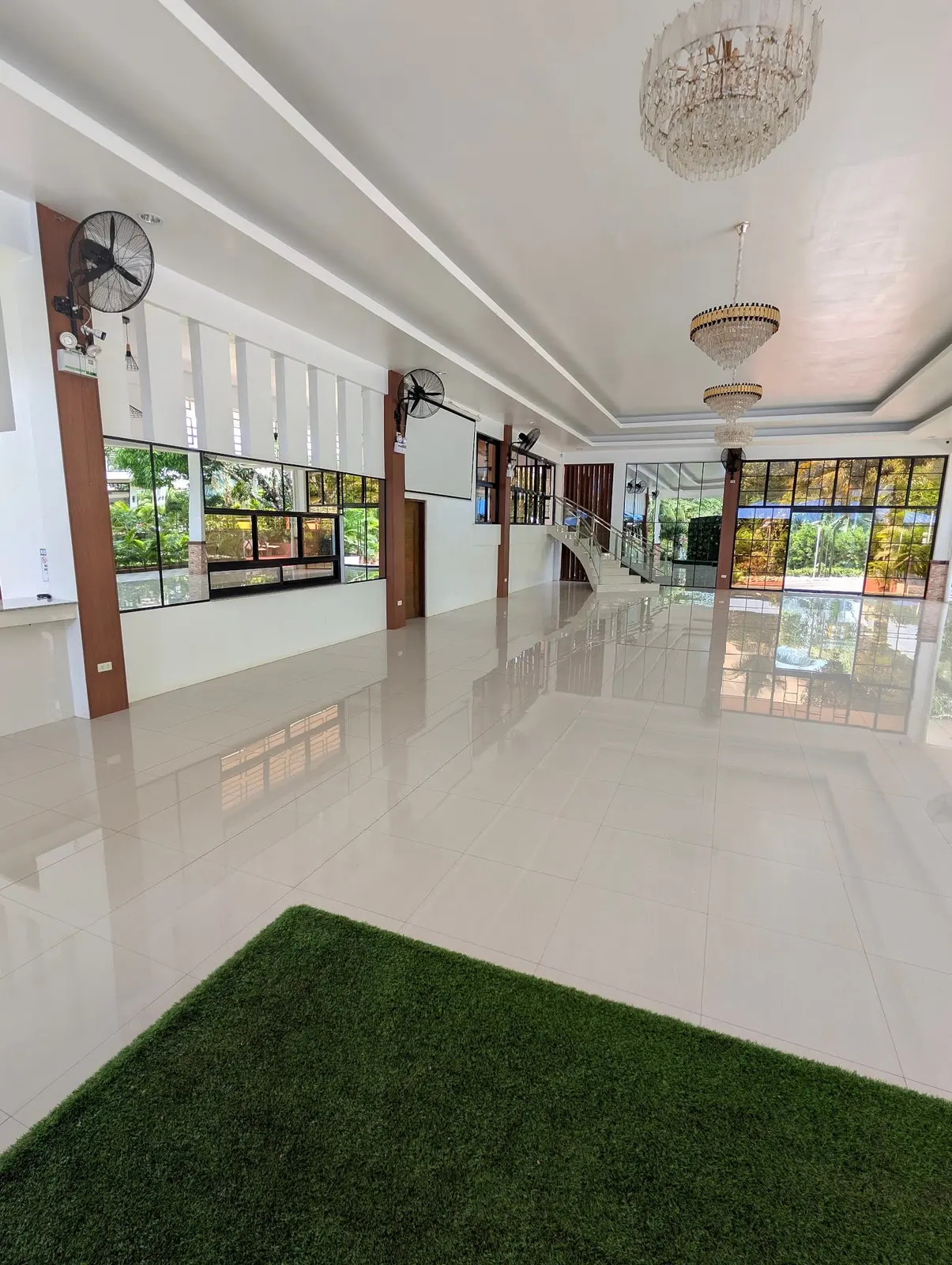 Inside the venue hall: white floor, chandelier and wide windows to the garden