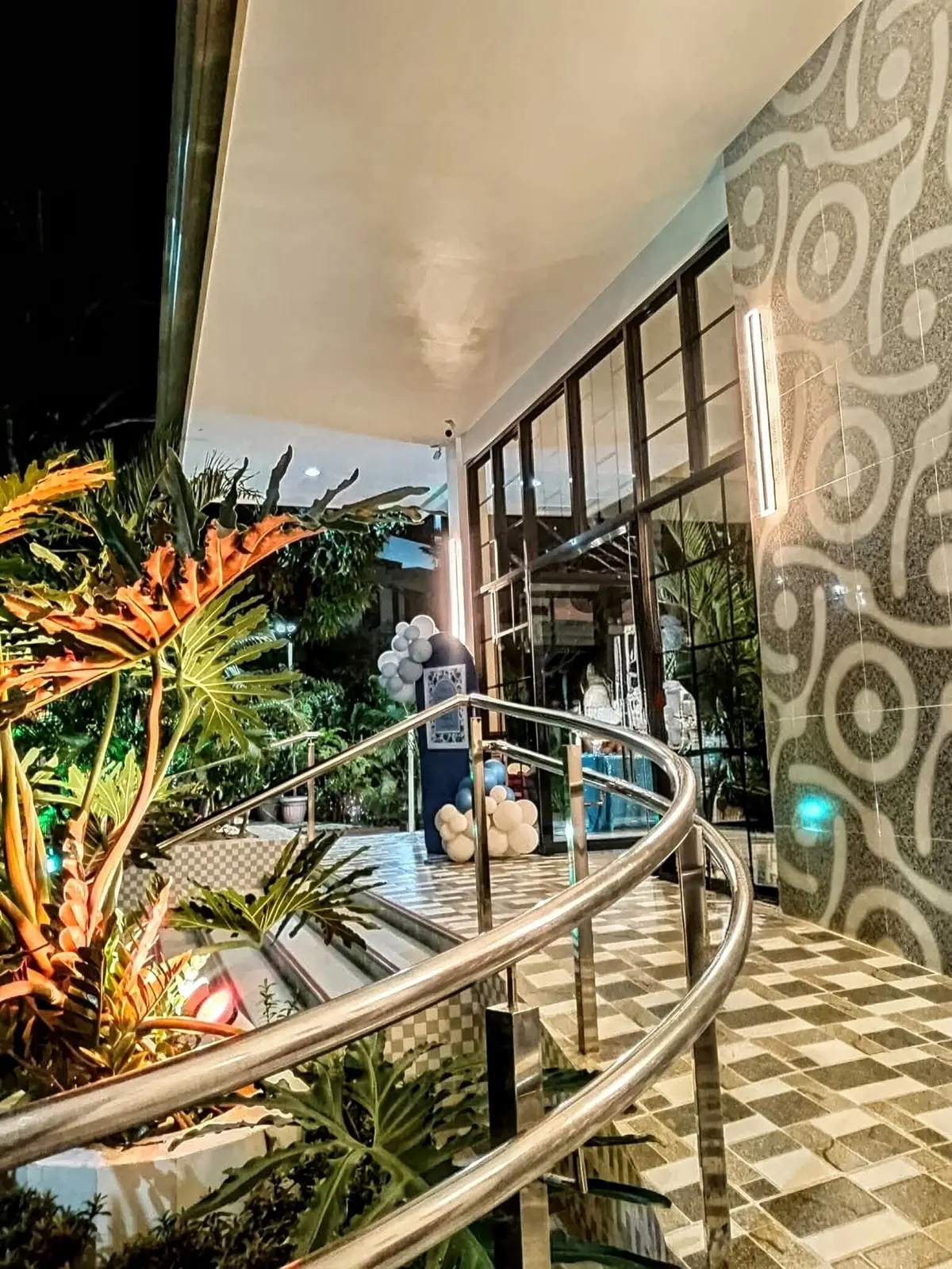 The lit curved stair and patterned wall at the hall entrance at night