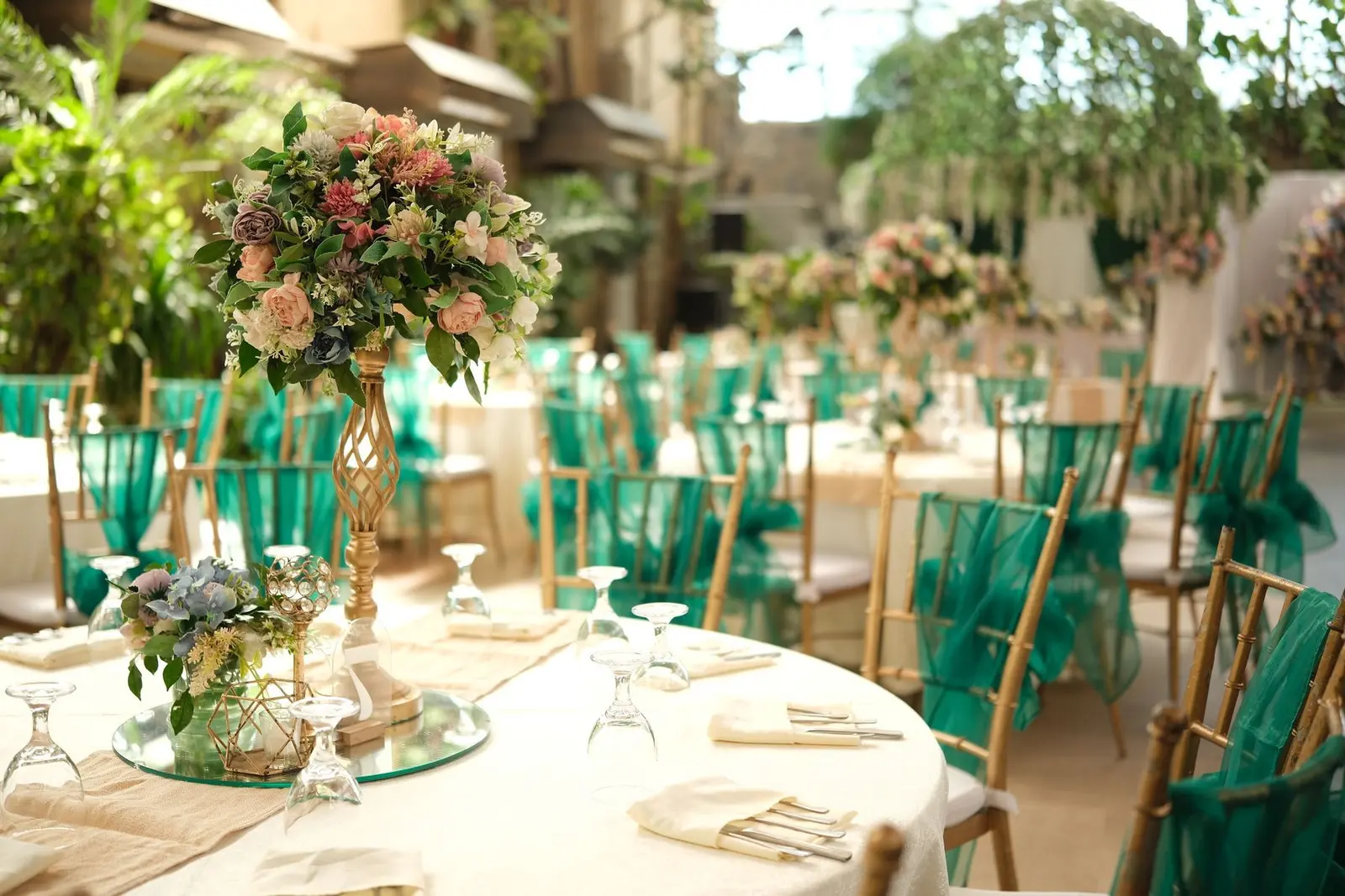 Sample styling: round reception tables with tall floral centerpieces and green chair sashes